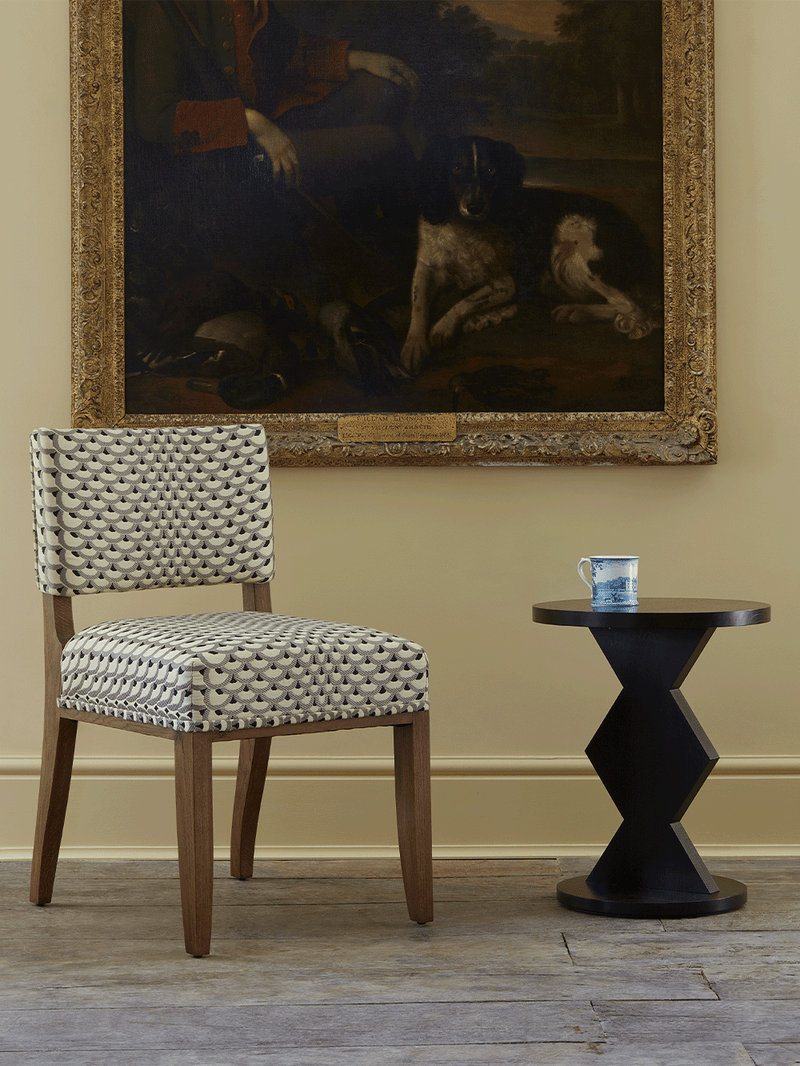 Dining chair and side table in a room with a large painting on the wall.