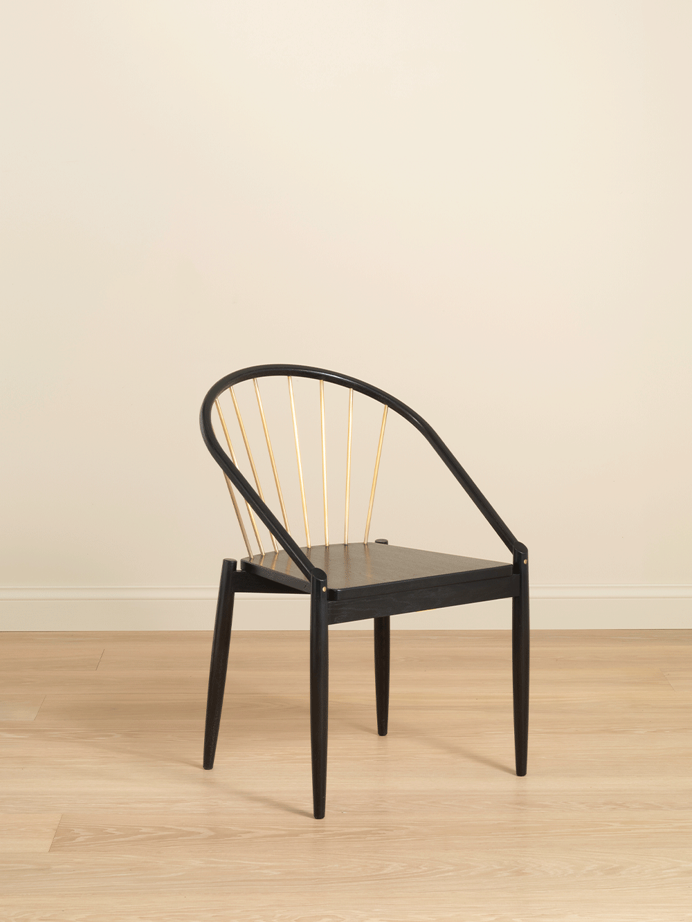 Black oak chair with curved backrest against a beige background. 