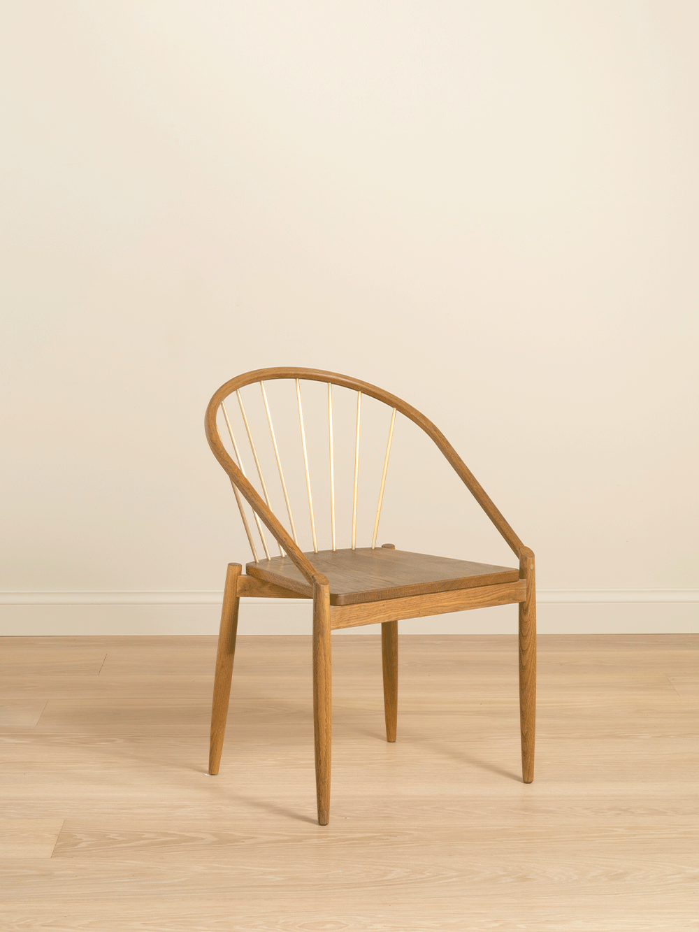 Wooden chair with curved backrest on a beige floor and wall.