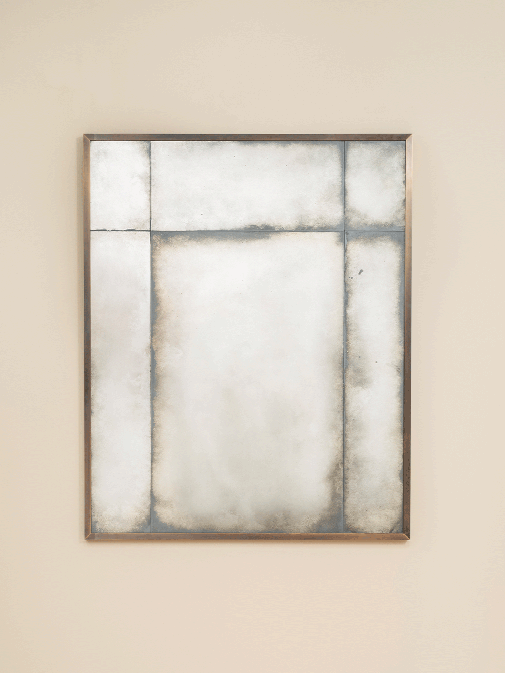 Wall mirror with a brass frame on a beige wall. 