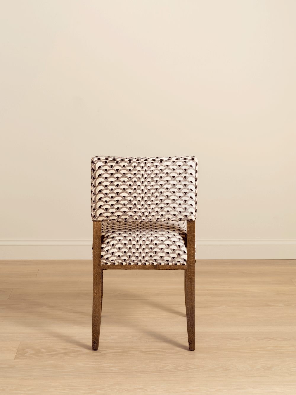 Chair with woven backrest and seat on a wooden floor against a beige wall. 