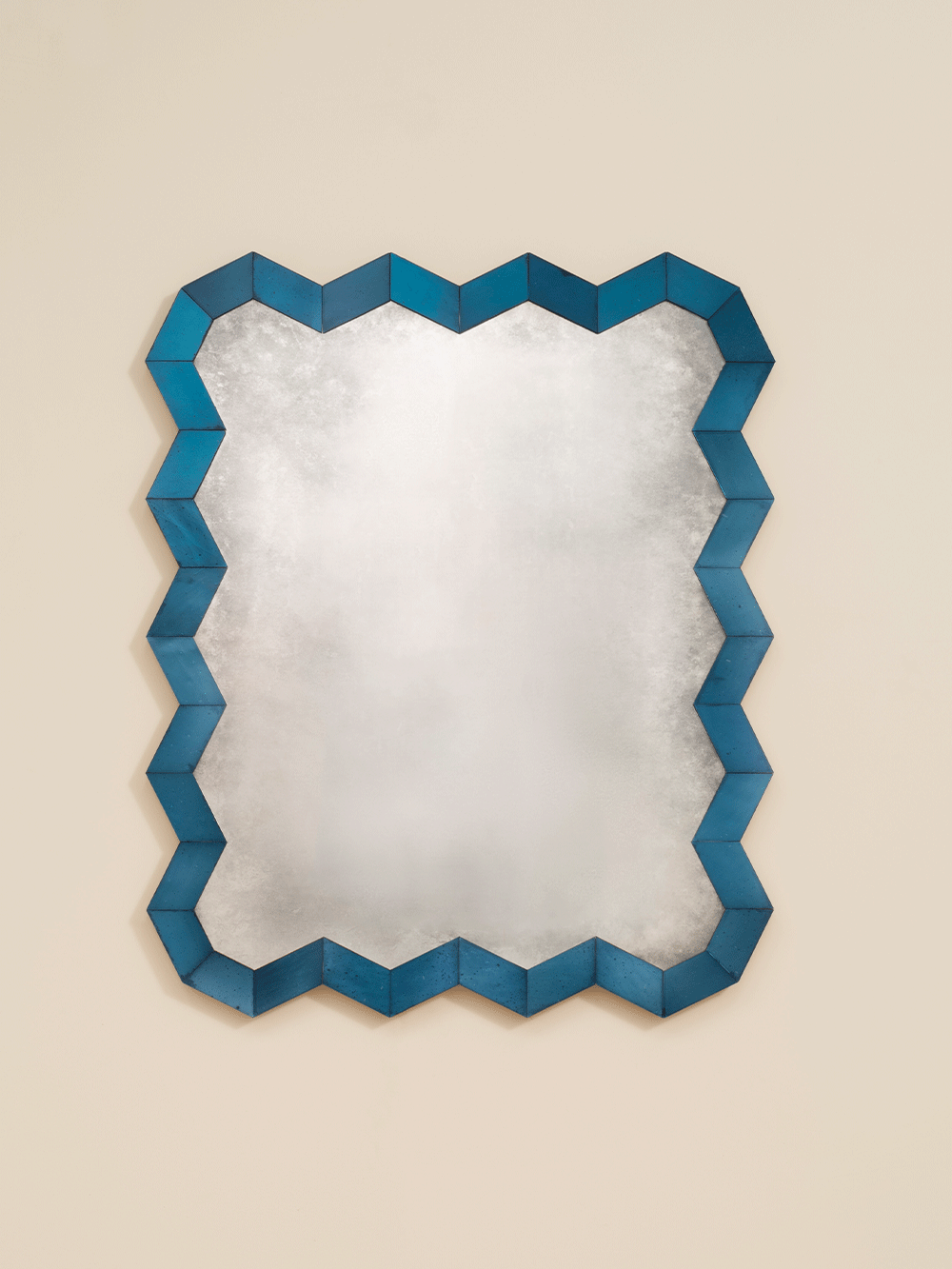 Mirror with a blue zigzag frame on a beige wall. 