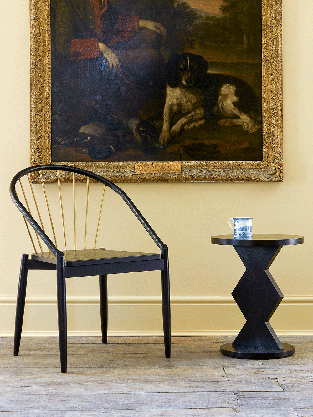 Black oak chair and side table in a room with a large framed painting on the wall.