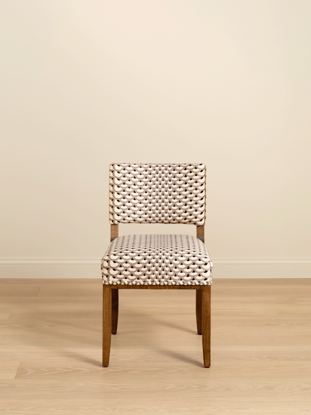 Dining chair with woven backrest and seat on a wooden floor against a beige wall.
