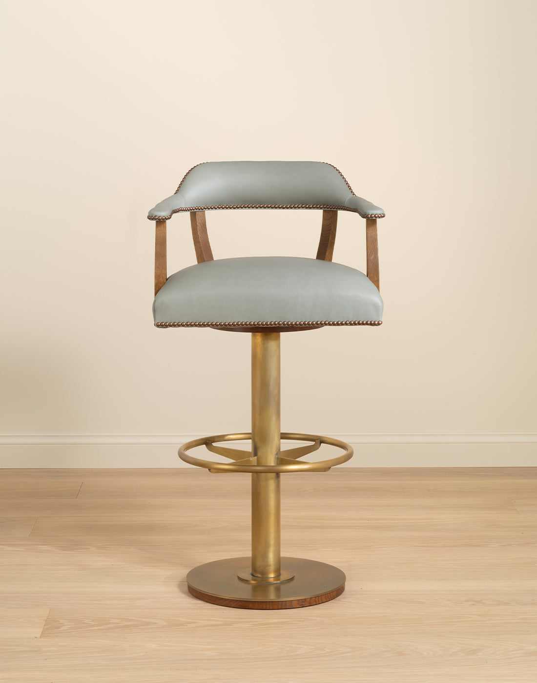 Bar stool with leather seat and brass metal base on a wooden floor.