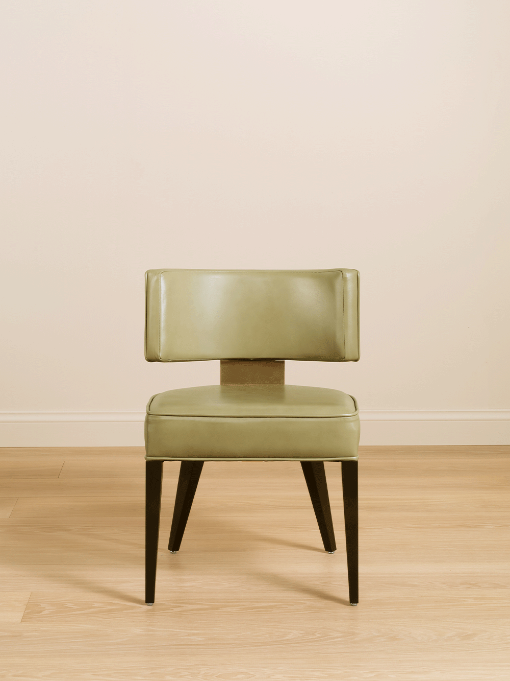 Green chair on a wooden floor with a beige wall background.