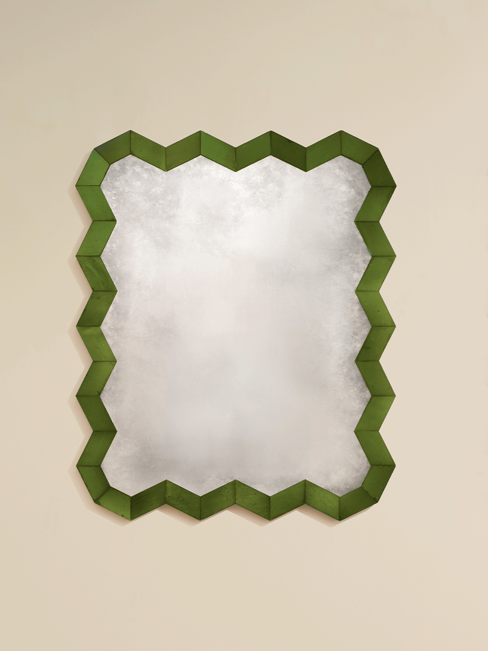 Decorative mirror with a green zigzag frame on a beige background.