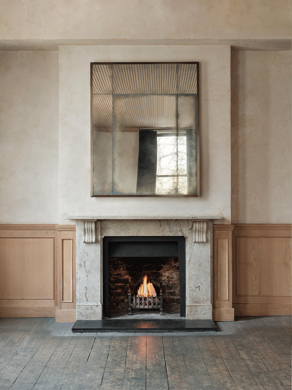 Fireplace with an overmantel mirror above it in a room with wooden paneling.