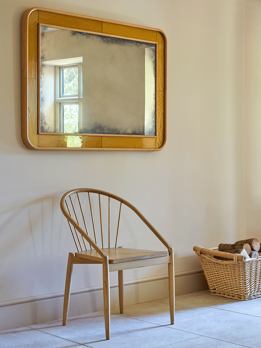 Wooden chair and mirror in a room with a basket on the floor.