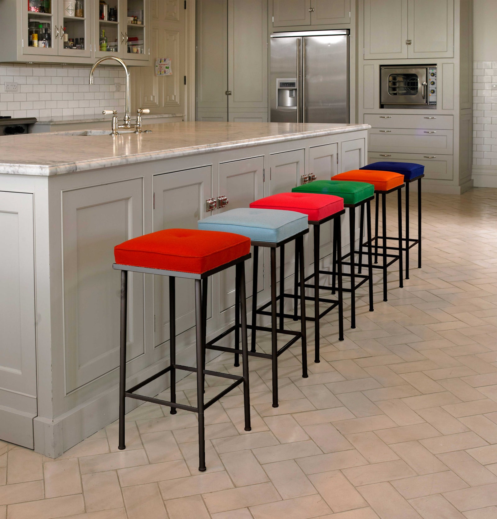 Colourful bar stools lined up against a kitchen counter.