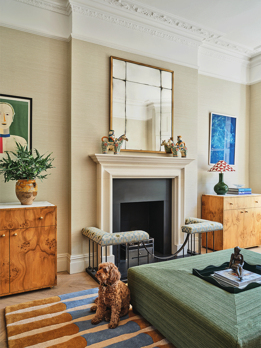 Cozy living room with a dog sitting on the floor, green coffee table, wooden cabinets and fireplace.