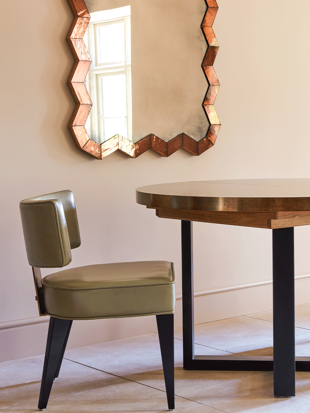 Green dining chair and brass table in a room with a decorative mirror on the wall.