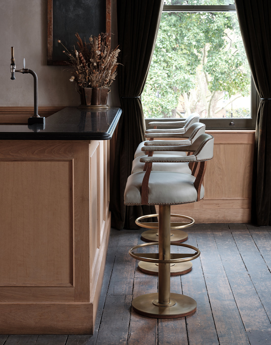 Bar area with wooden counter and bar stools near a window.