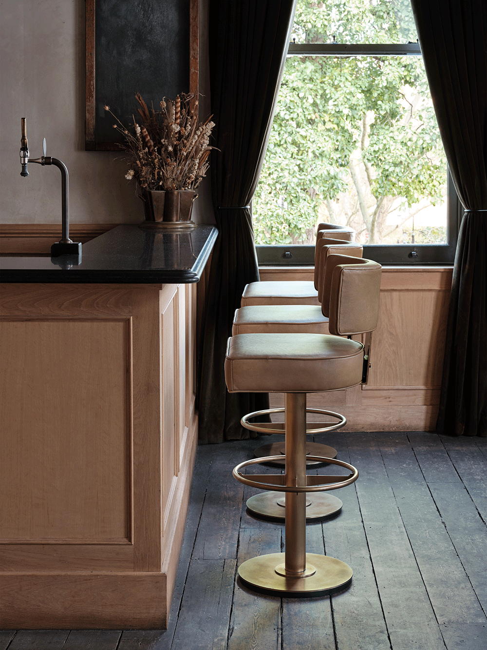 Modern pub with leather bar stools and a window view.