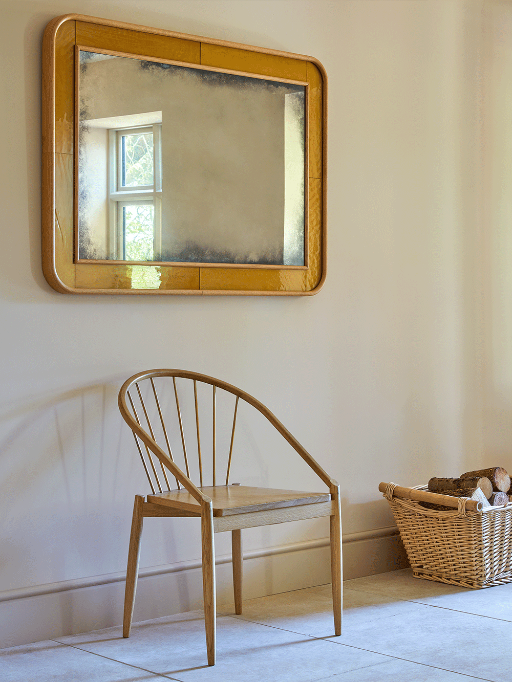 Wooden chair and gold mirror in a room with a basket on the floor.