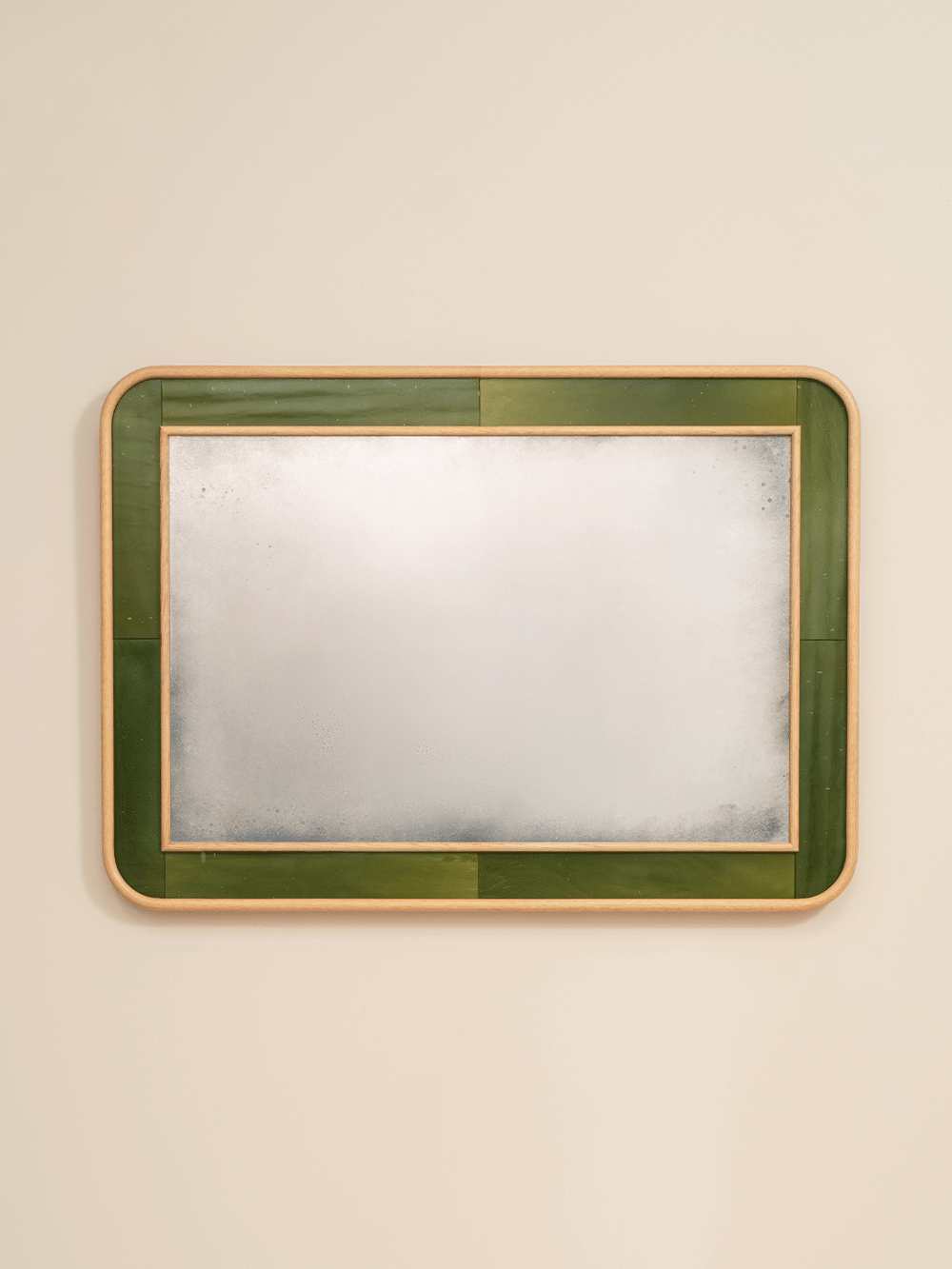 Rectangular mirror with green frame on a beige wall.