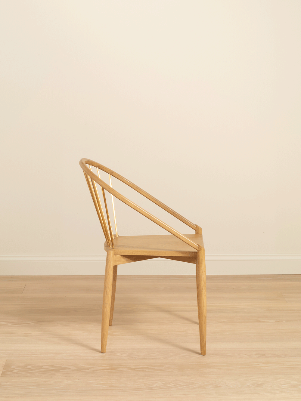 Oak chair on a wooden floor with a beige wall background. 