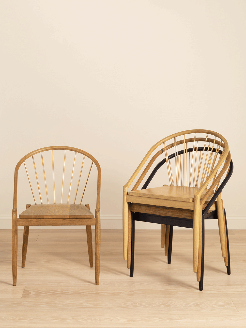 Stacked wooden chairs with different coloured finished on a beige background. 