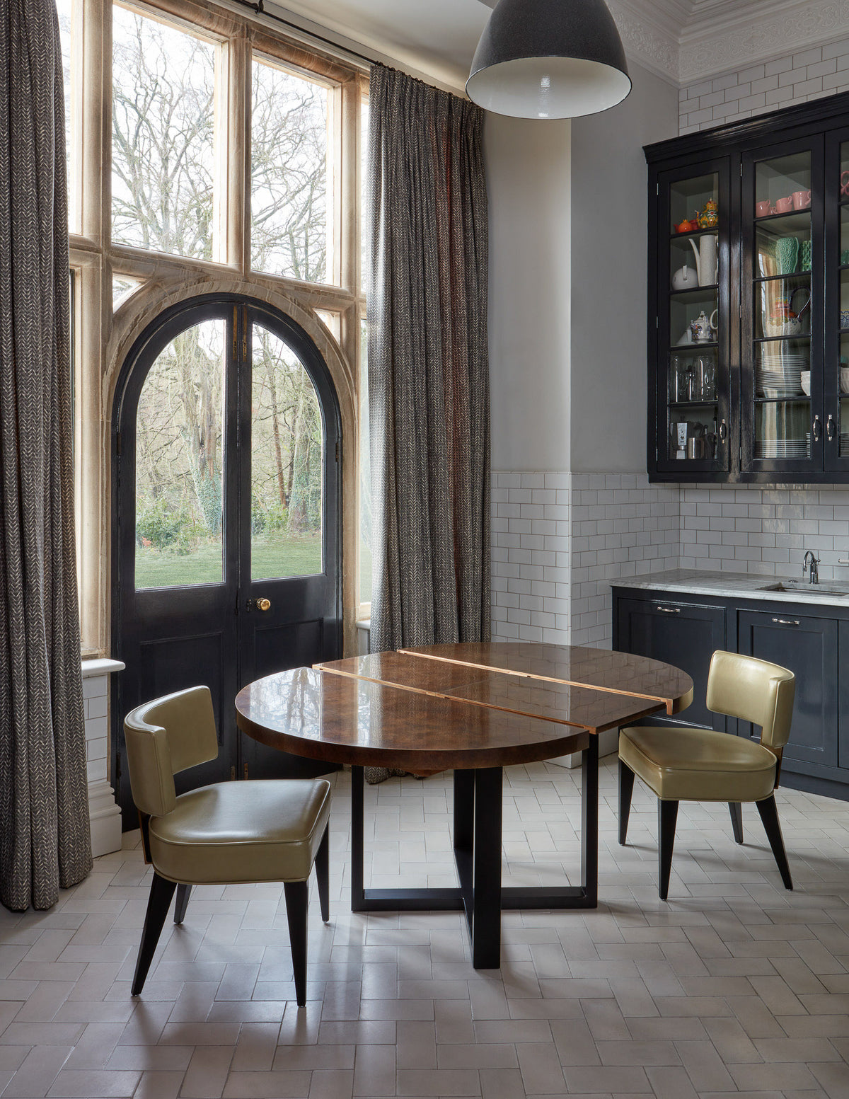 Modern kitchen with round table and chairs near large windows.