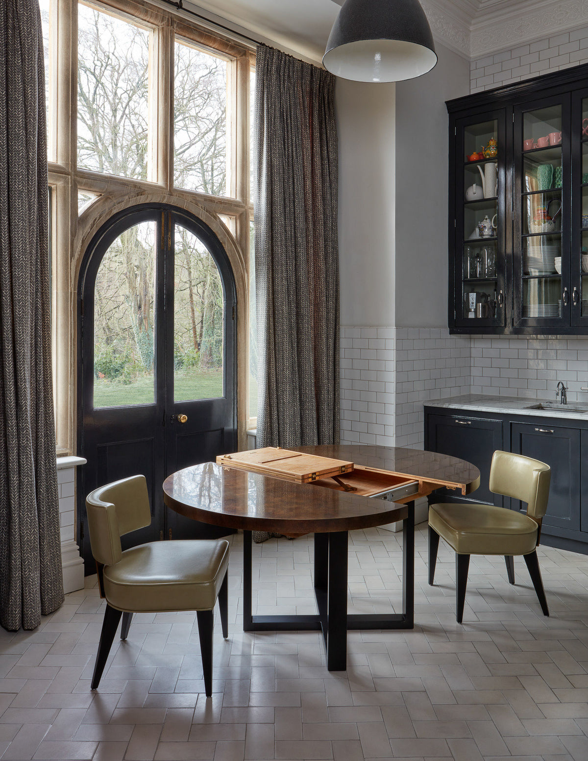 Modern kitchen with round table and chairs near large windows.