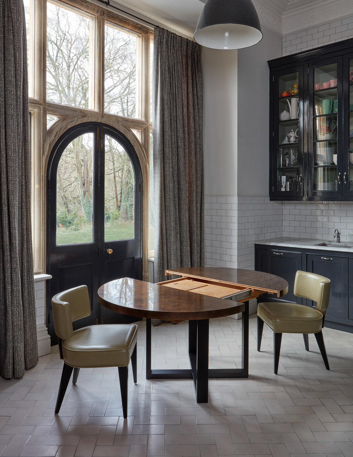 Modern kitchen with round table and chairs near large windows.