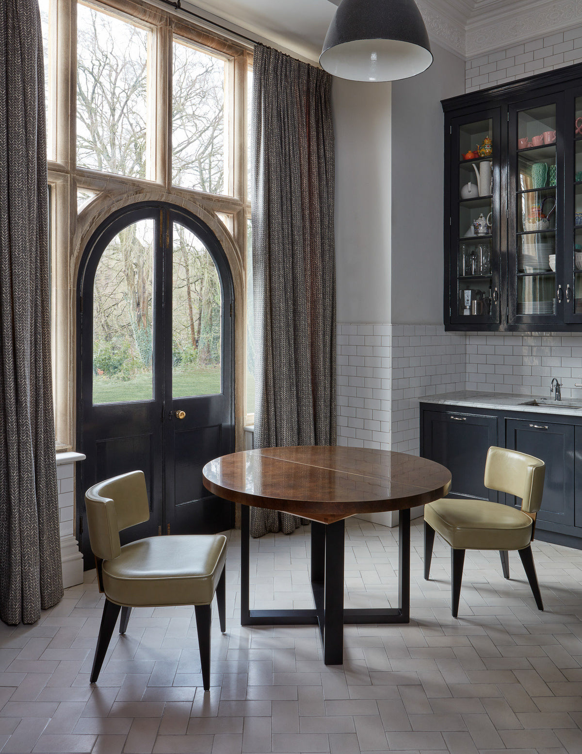 Modern kitchen with round table and chairs near large windows.