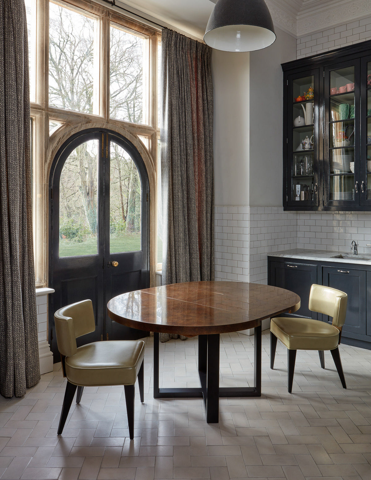 Modern kitchen with round table and chairs near large windows.