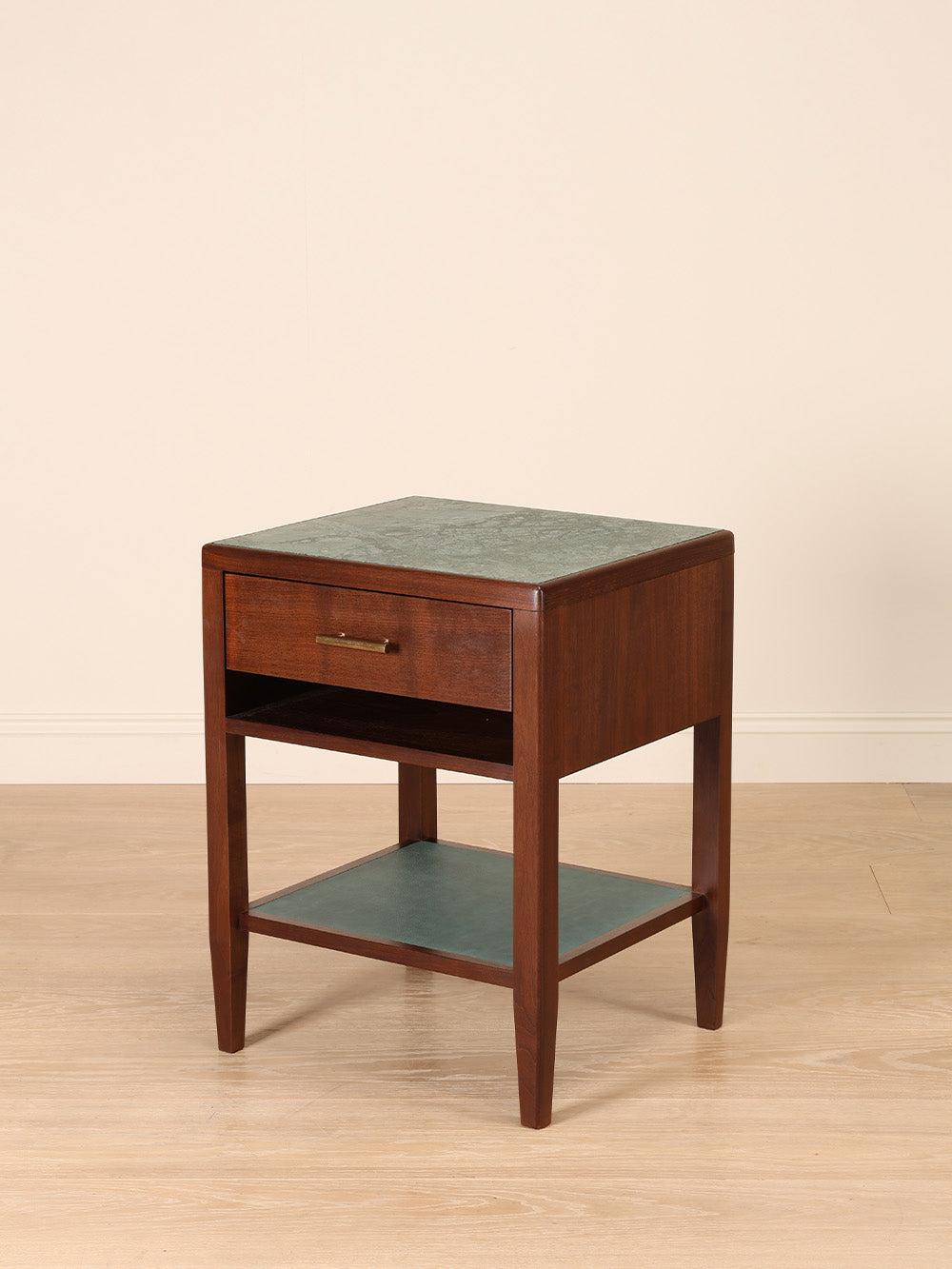 Wooden bedside table with marble top on a beige background.