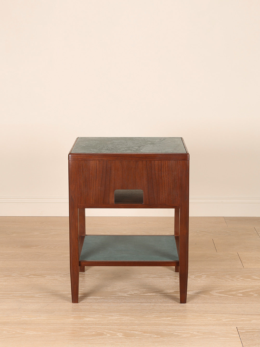 Wooden bedside table with marble top on a beige background.