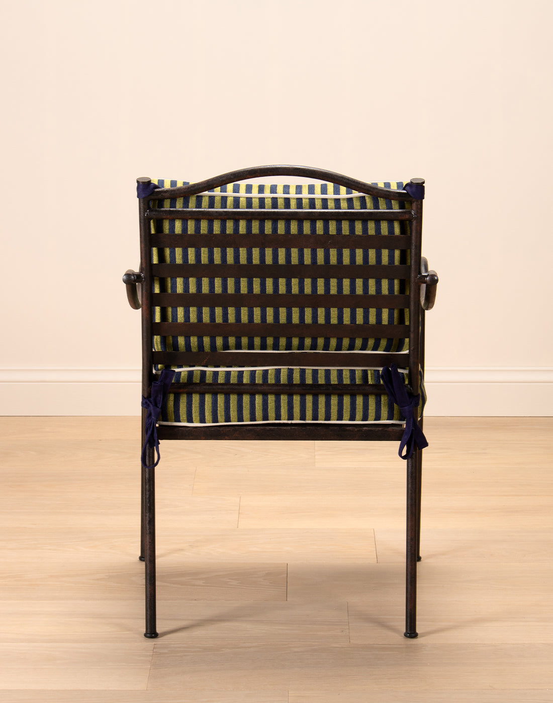 Steel chair with black frame and yellow cushion on a beige floor and wall.