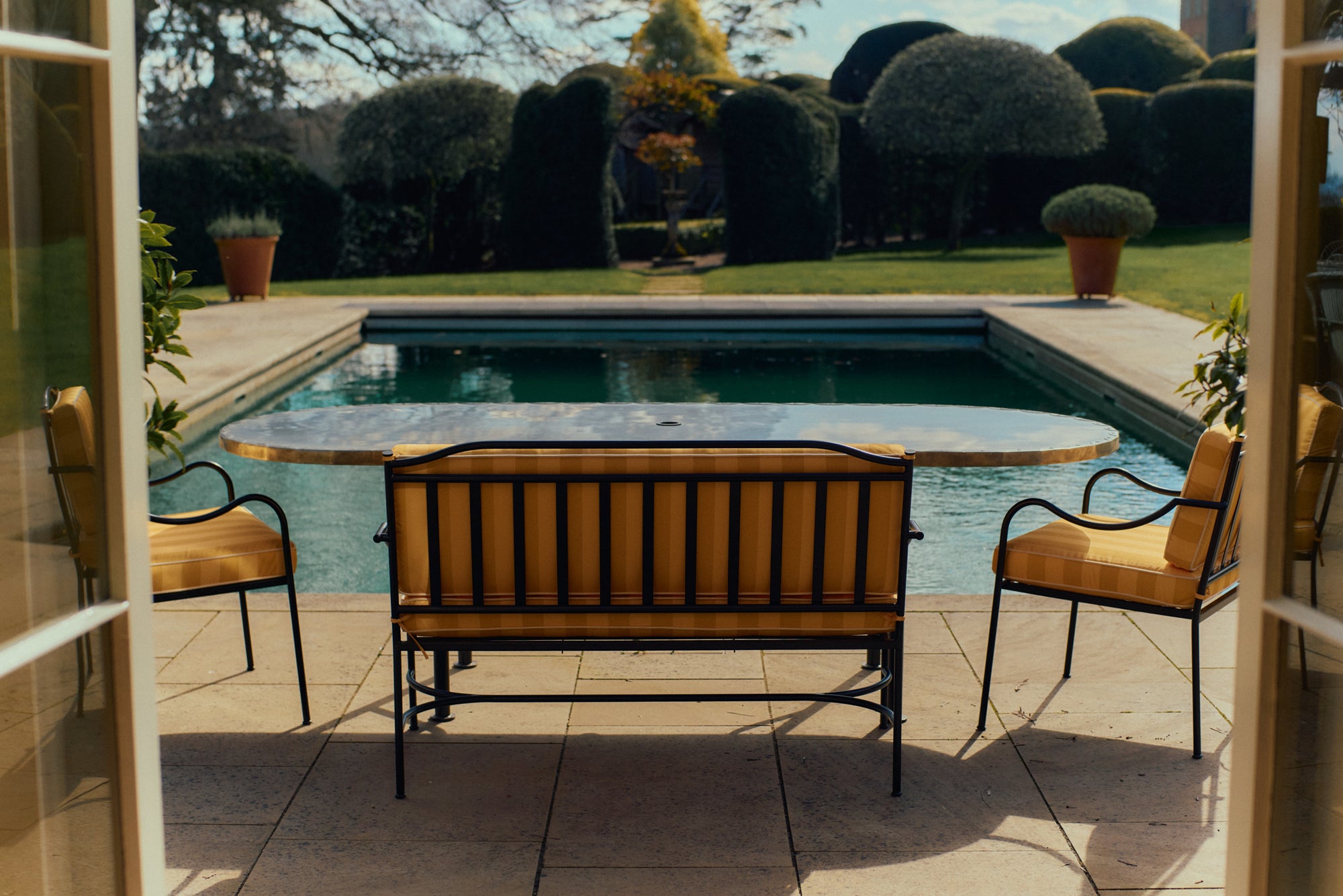Outdoor table, chair and bench near a pool.