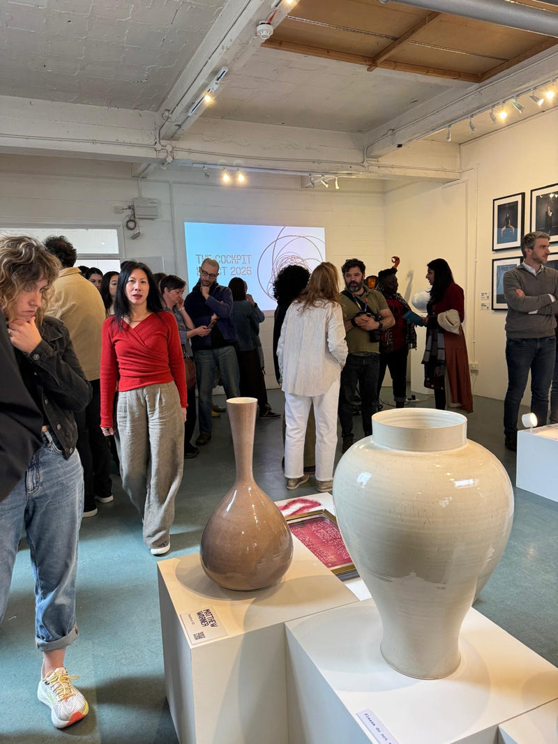 Art gallery with visitors and two ceramic vases on display.