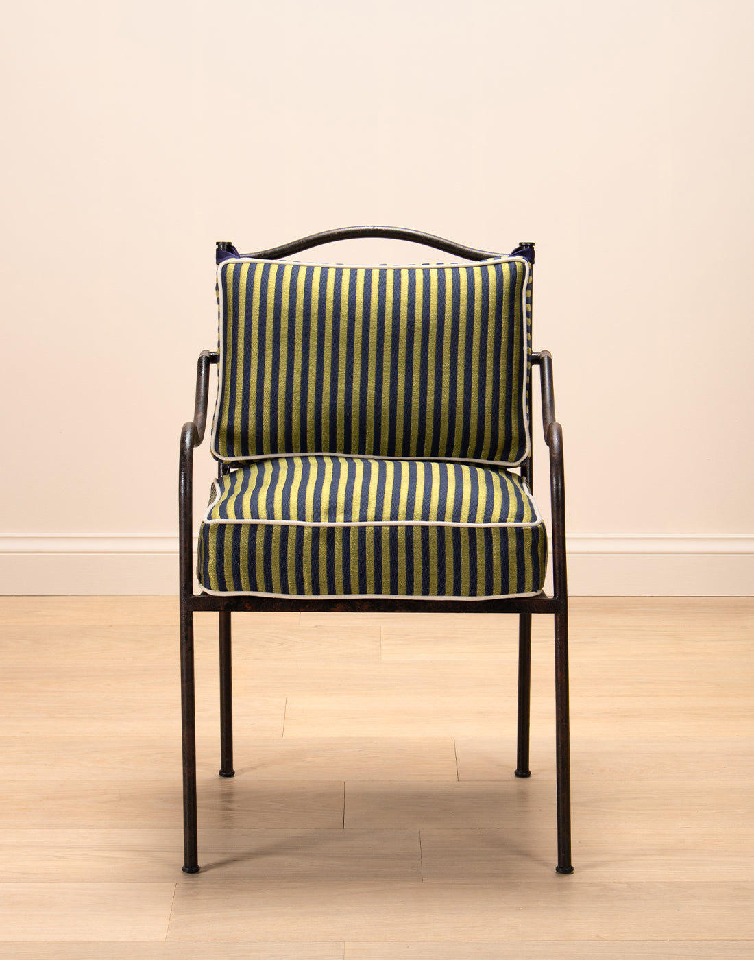 Chair with striped cushions on a wooden floor and beige wall background.