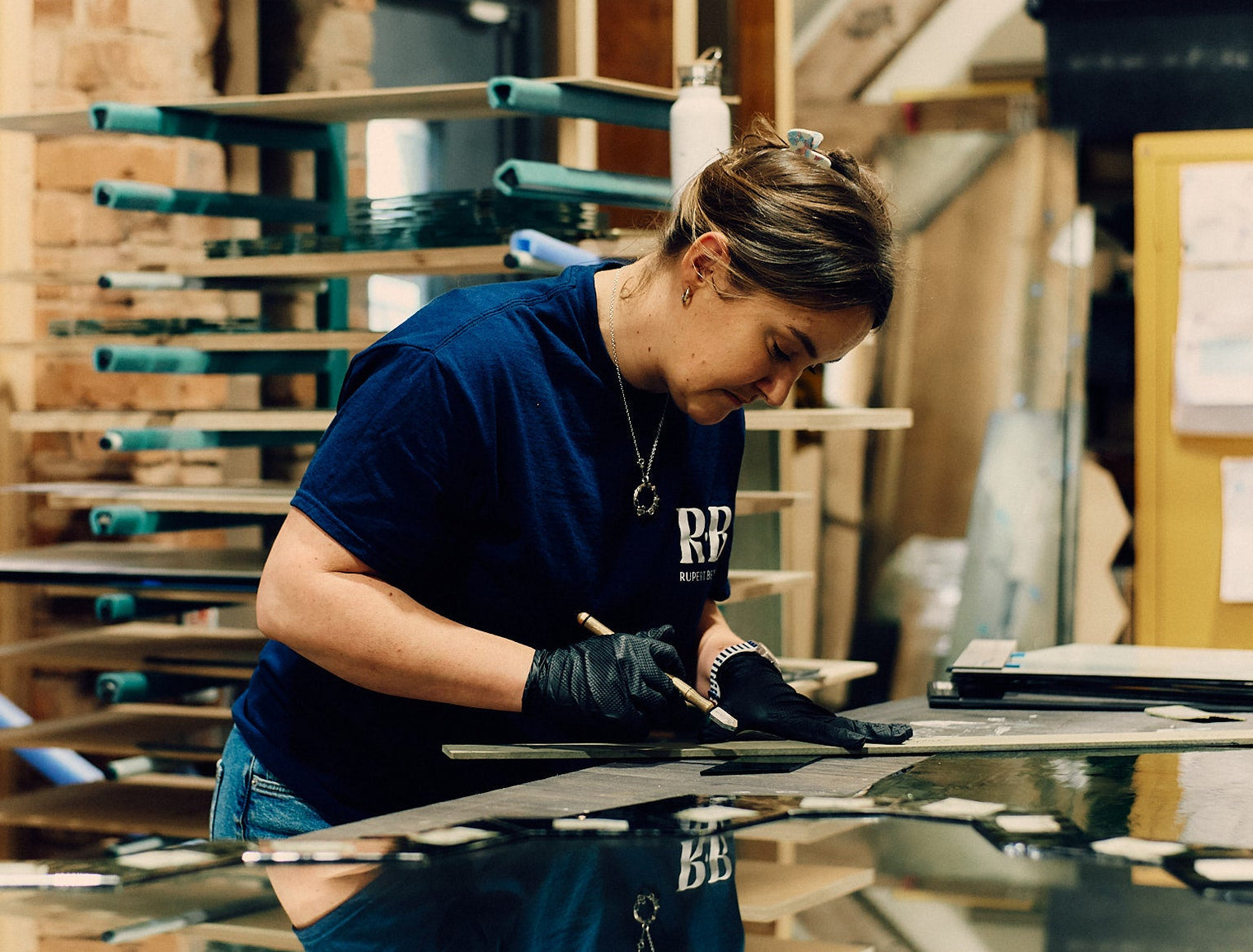 Person working on a table with glass materials in a workshop setting. 