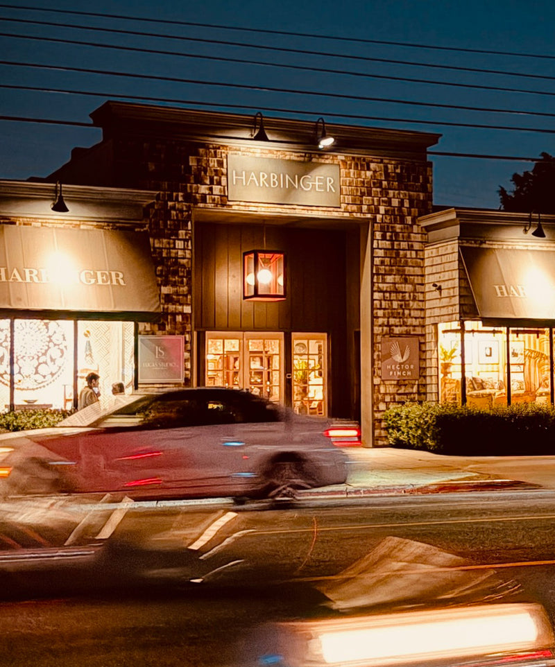 Harbinger storefront at night with a car in front.