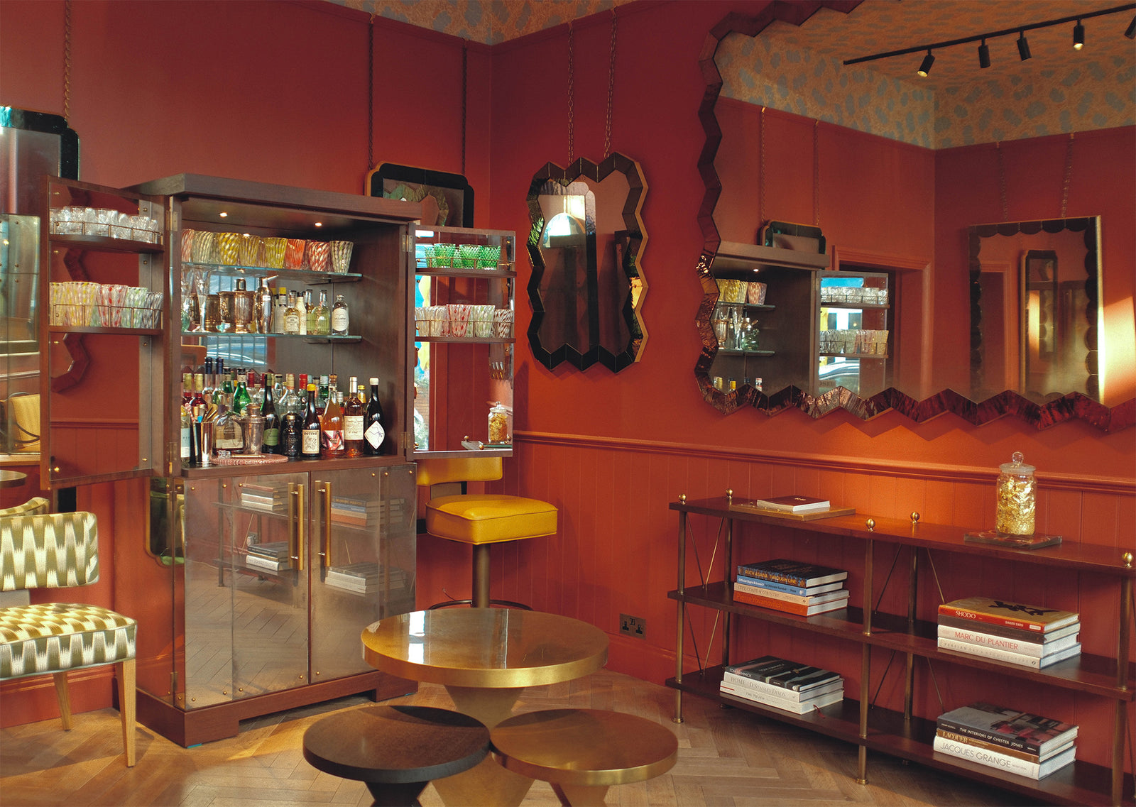 Bar area with red walls, bar cabinet and shelves with books and bottles.