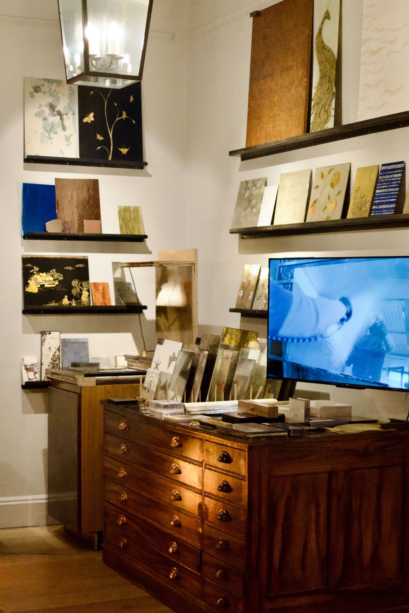 Display of material samples on shelves with a television in the background.