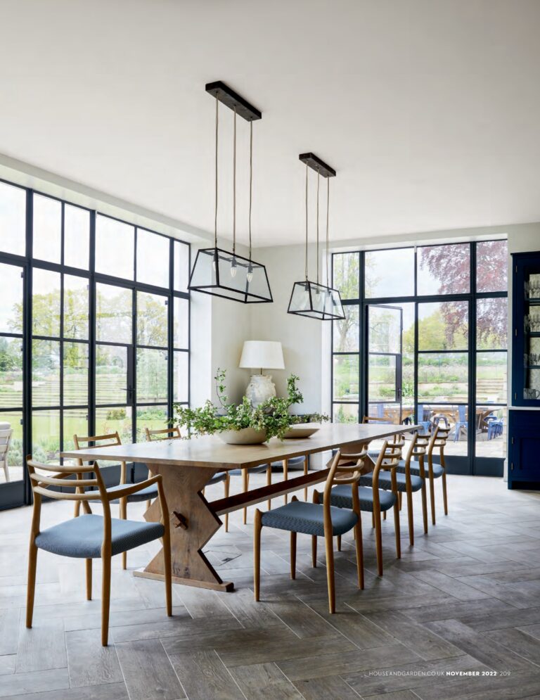 Modern dining room with wooden table and chairs near large windows.