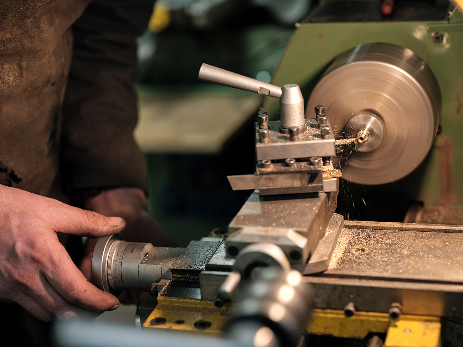Person controlling a machine in a metal workshop setting.