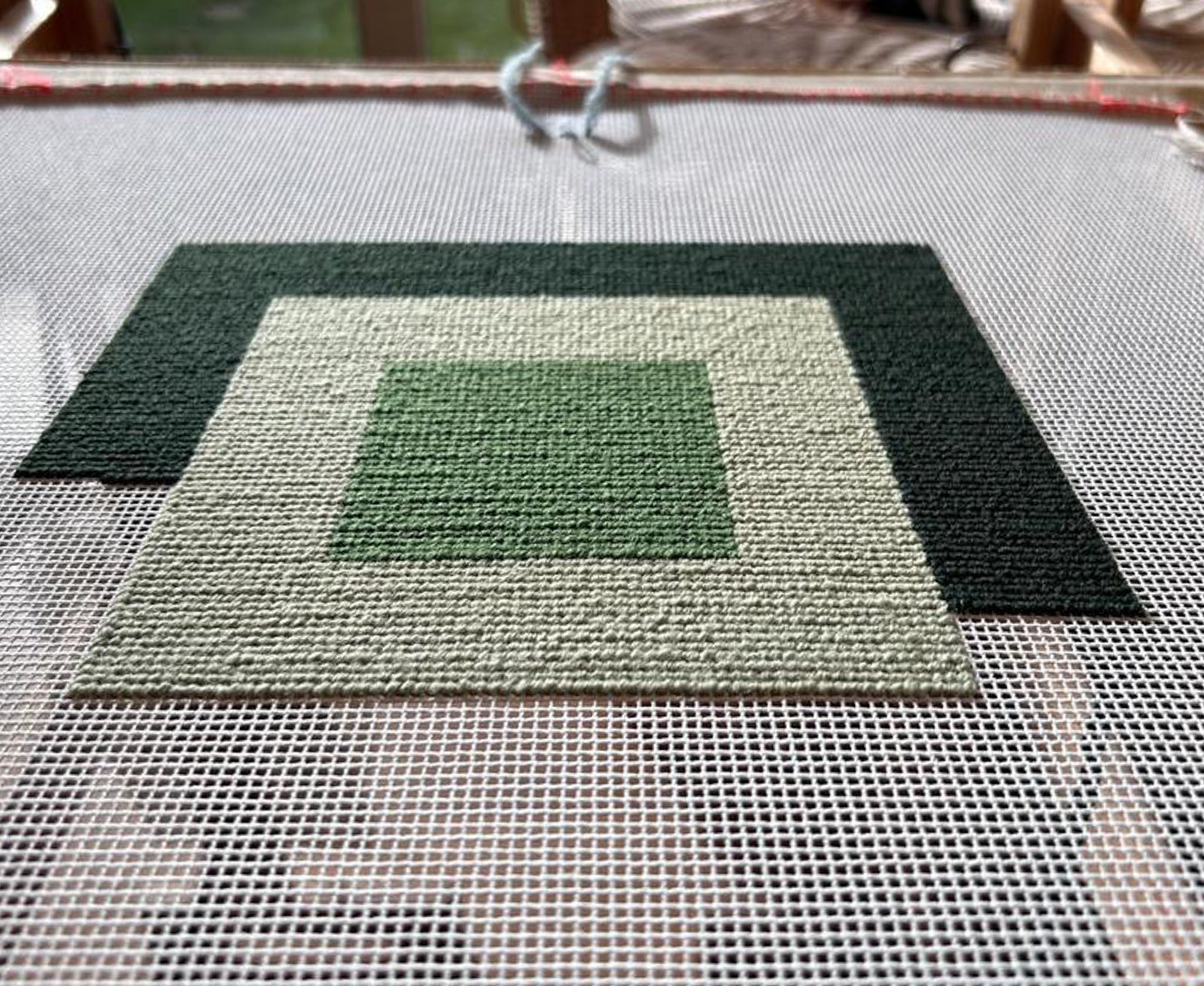 Green needlepoint with a textured pattern.