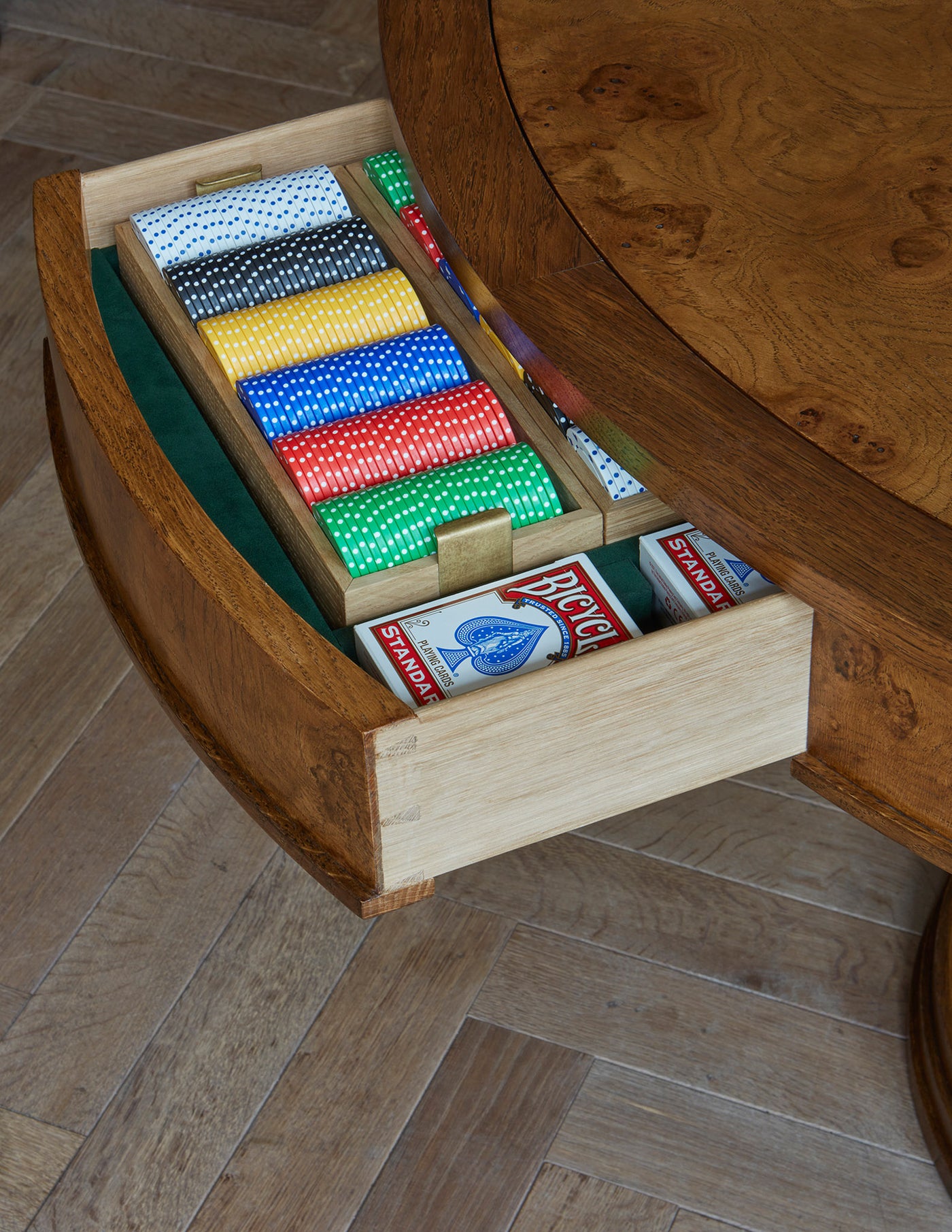 Close-up of an oak table drawer with poker chips and game accessories inside. 