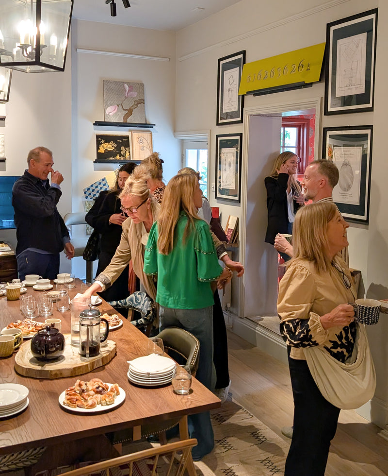 People gathered around a table in a room with framed pictures on the wall.