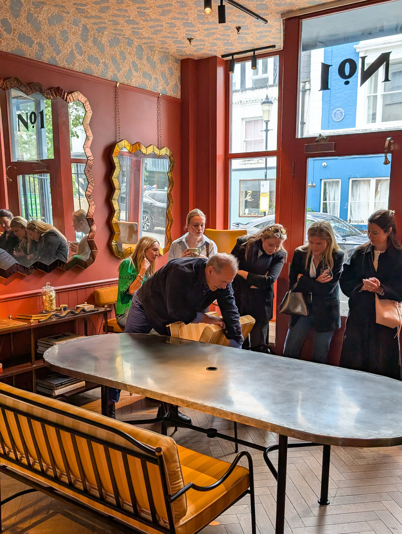 People in a furniture showroom with large windows and decorative mirrors.