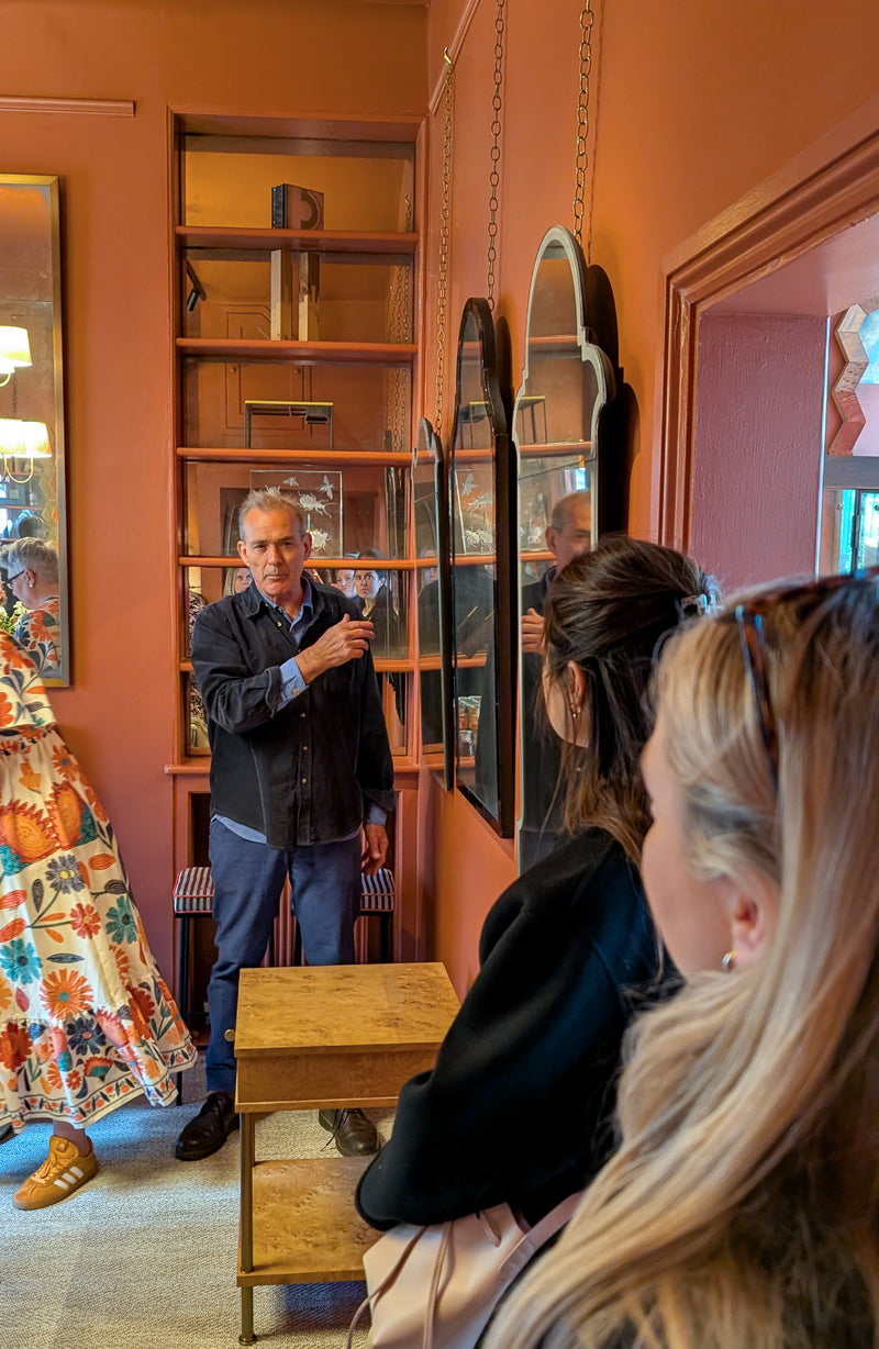 Person talking to a group with mirrors hanging on a wall.