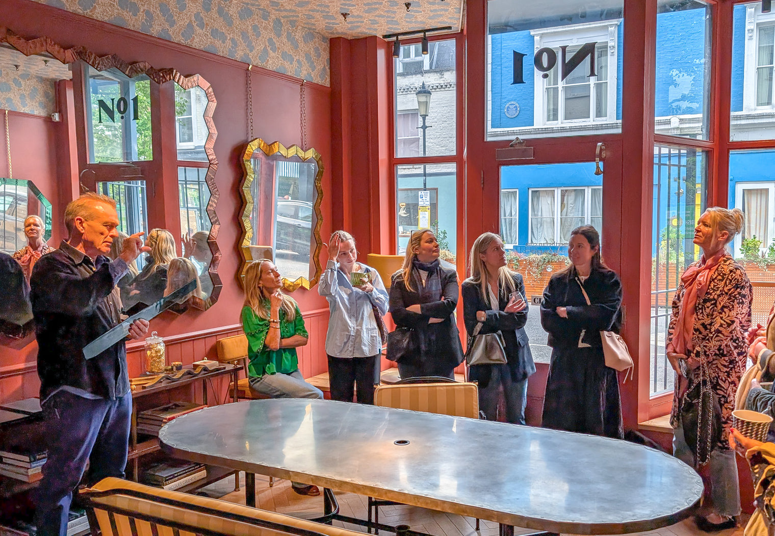 Group of people in a modern furniture showroom with large windows and colourful exterior.