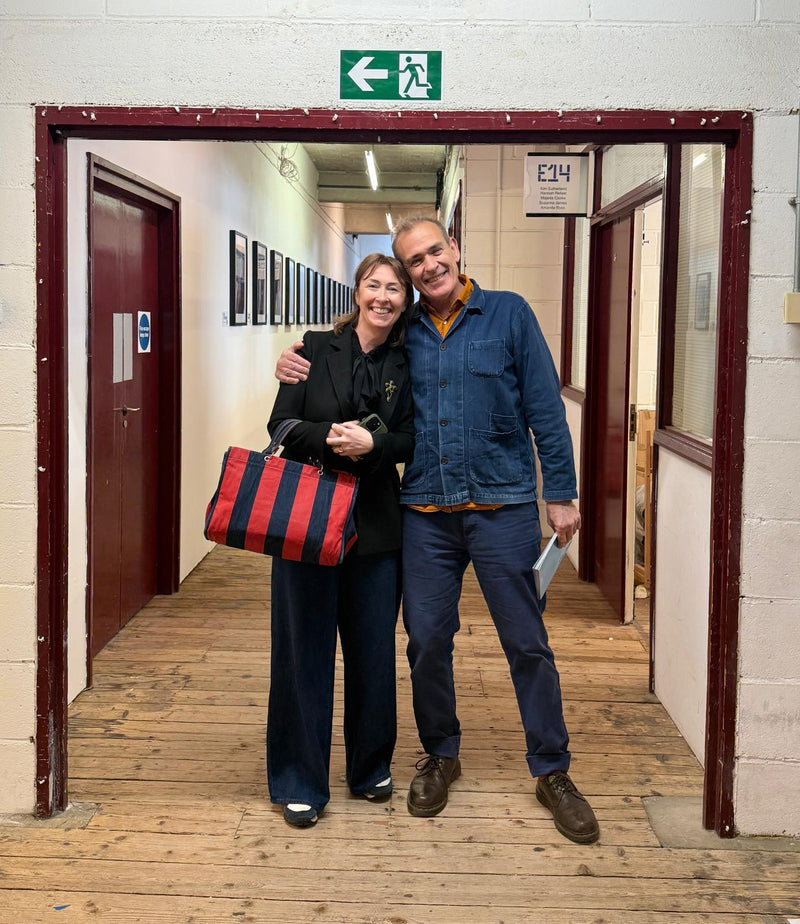 Two people standing in a hallway with a red and black bag.
