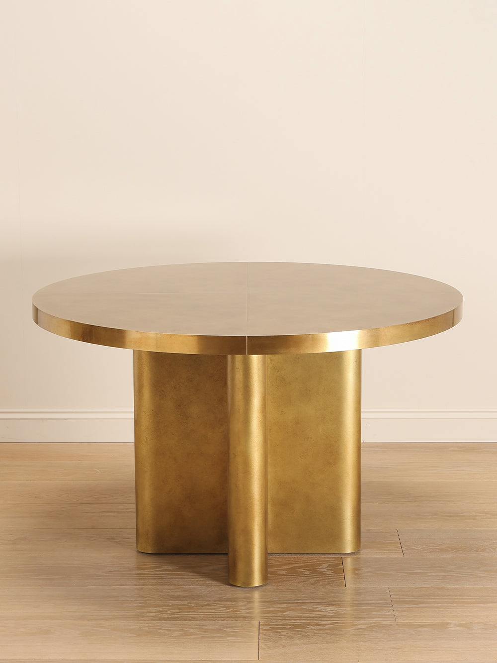Brass round table with a unique geometrical base design on a wooden floor.