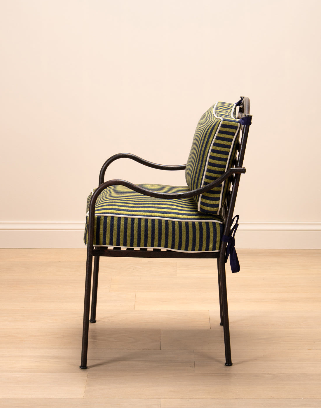 Steel chair with striped cushions on a wooden floor and beige wall background.