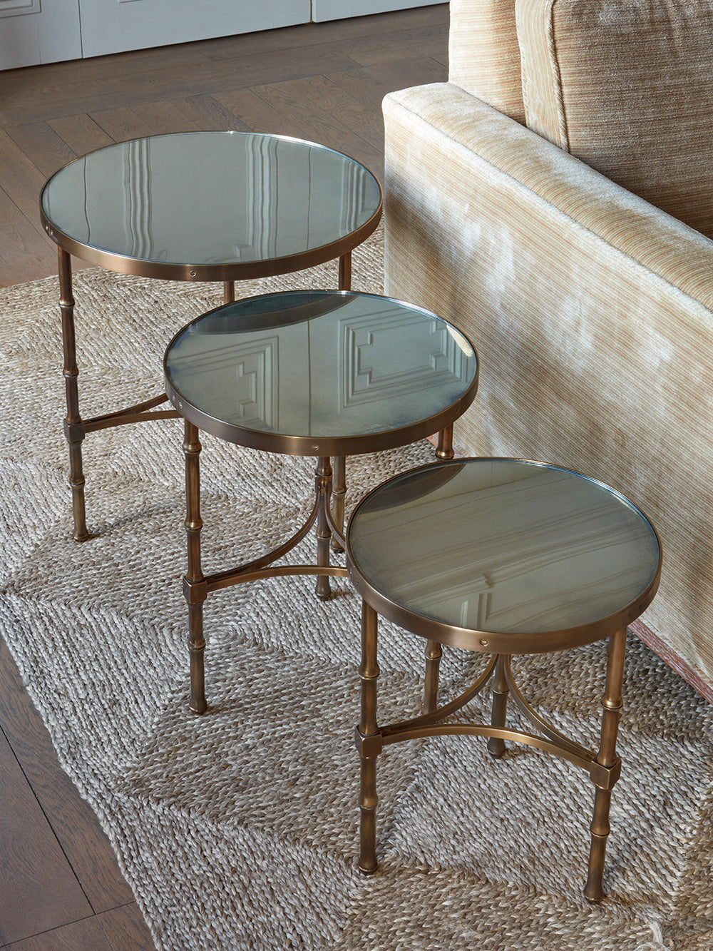 Brass side tables with glass tops in a line in a sitting room setting.