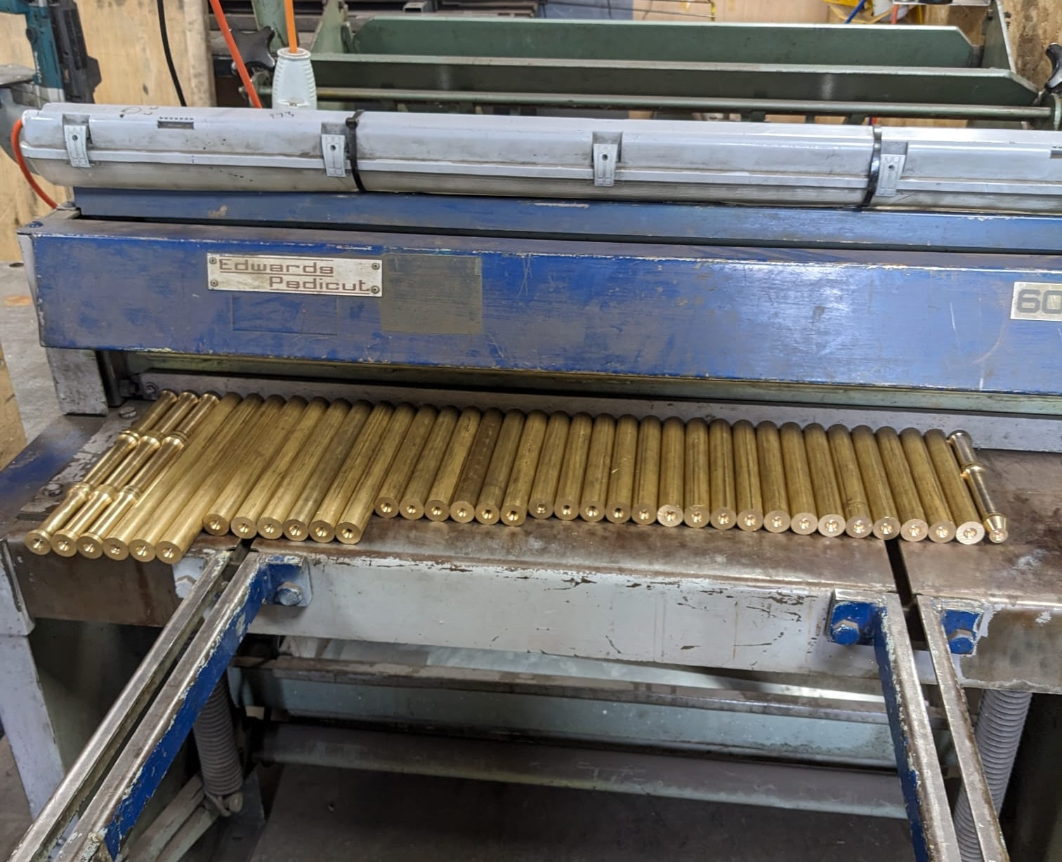 Machine with brass rods on a workshop background.